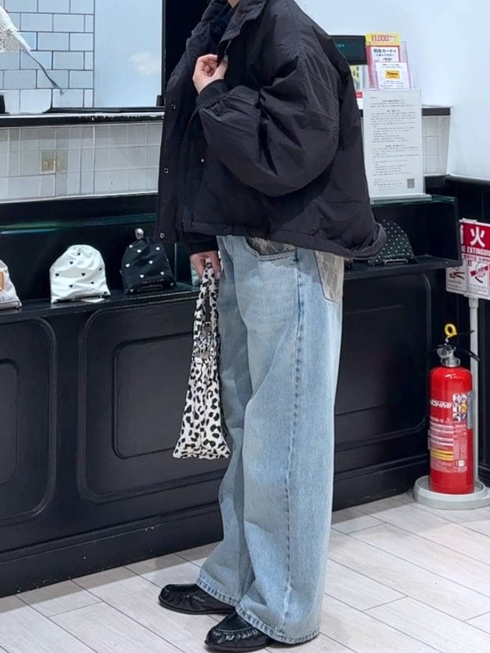 ブラック系のその他アウター、その他のショルダーバッグ、ブルー系のデニムパンツを着用したレディースの冬コーディネートの2枚目の写真