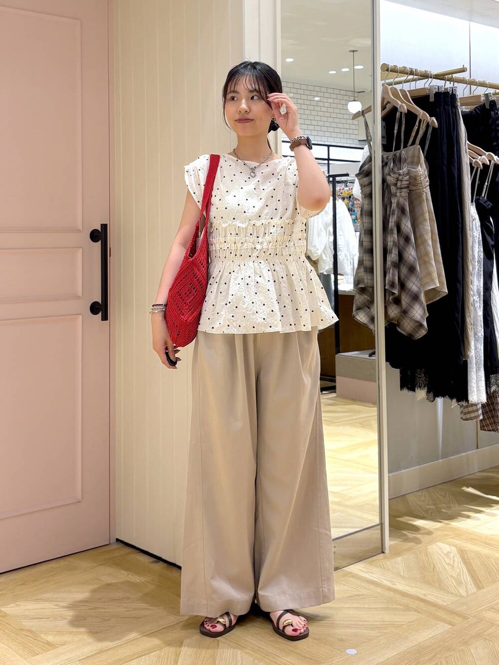 ベージュ系のデニムパンツ、ブラウン系のサンダル、レッド系のトートバッグを着用したレディースの夏コーディネートの5枚目の写真