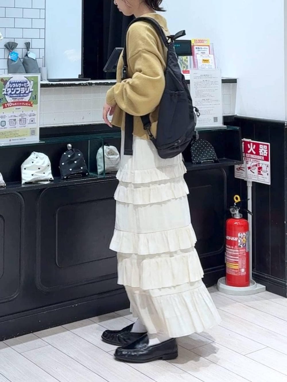 ブラック系のショルダーバッグ、ブラック系のローファー、ホワイト系のスカートを着用したレディースの冬コーディネートの2枚目の写真