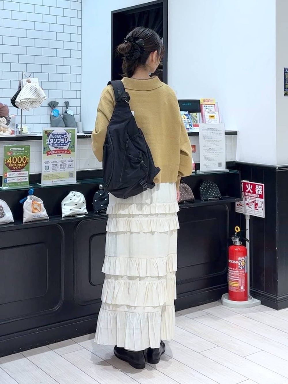 ブラック系のショルダーバッグ、ブラック系のローファー、ホワイト系のスカートを着用したレディースの冬コーディネートの3枚目の写真