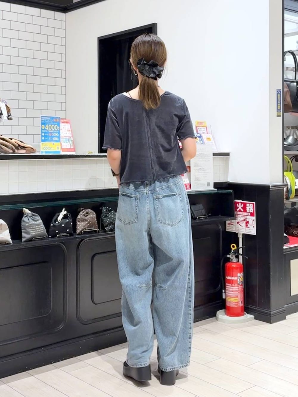 ブラック系のサンダル、ブルー系のデニムパンツ、ブラウン系のボストンバッグを着用したレディースの秋コーディネートの3枚目の写真