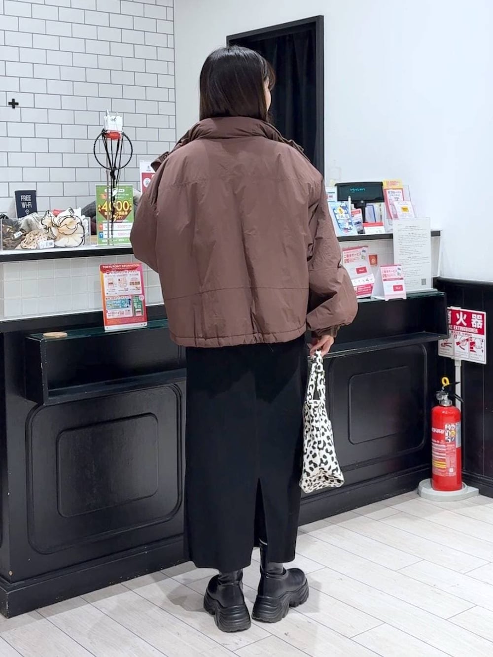 ブラック系のスカート、ブラウン系のその他アウター、ブラック系のブーツを着用したレディースの冬コーディネートの3枚目の写真