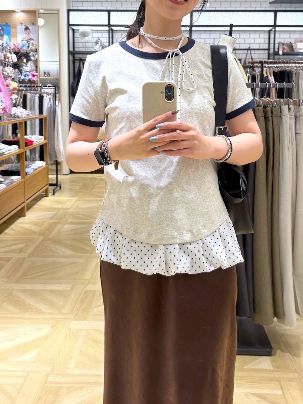 ブラウン系のスカート、ブラック系のサンダル、グレー系のTシャツ/カットソーを着用したレディースの春コーディネートの2枚目の写真