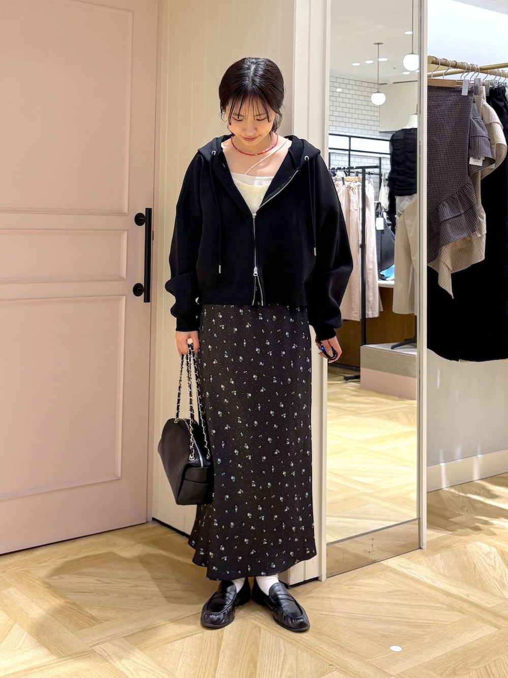 ブラック系のスカート、ブラック系のパーカー、ブラック系のショルダーバッグを着用したレディースの春コーディネートの4枚目の写真