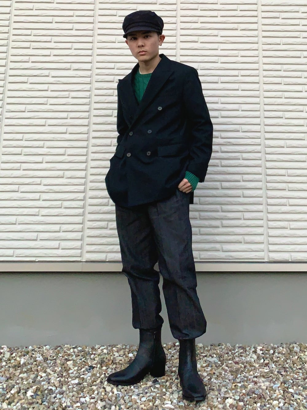 ブラック系のテーラードジャケット、グリーン系のニット/セーター、ブラック系のデニムパンツを着用したメンズの秋コーディネートの2枚目の写真