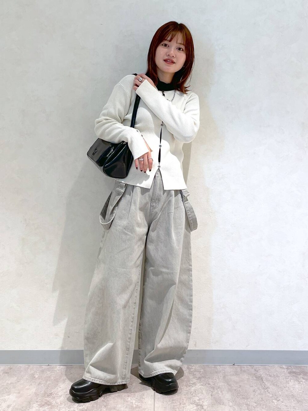 ブラック系のブーツ、ブラック系のショルダーバッグ、ブラック系のTシャツ/カットソーを着用したレディースの冬コーディネートの2枚目の写真