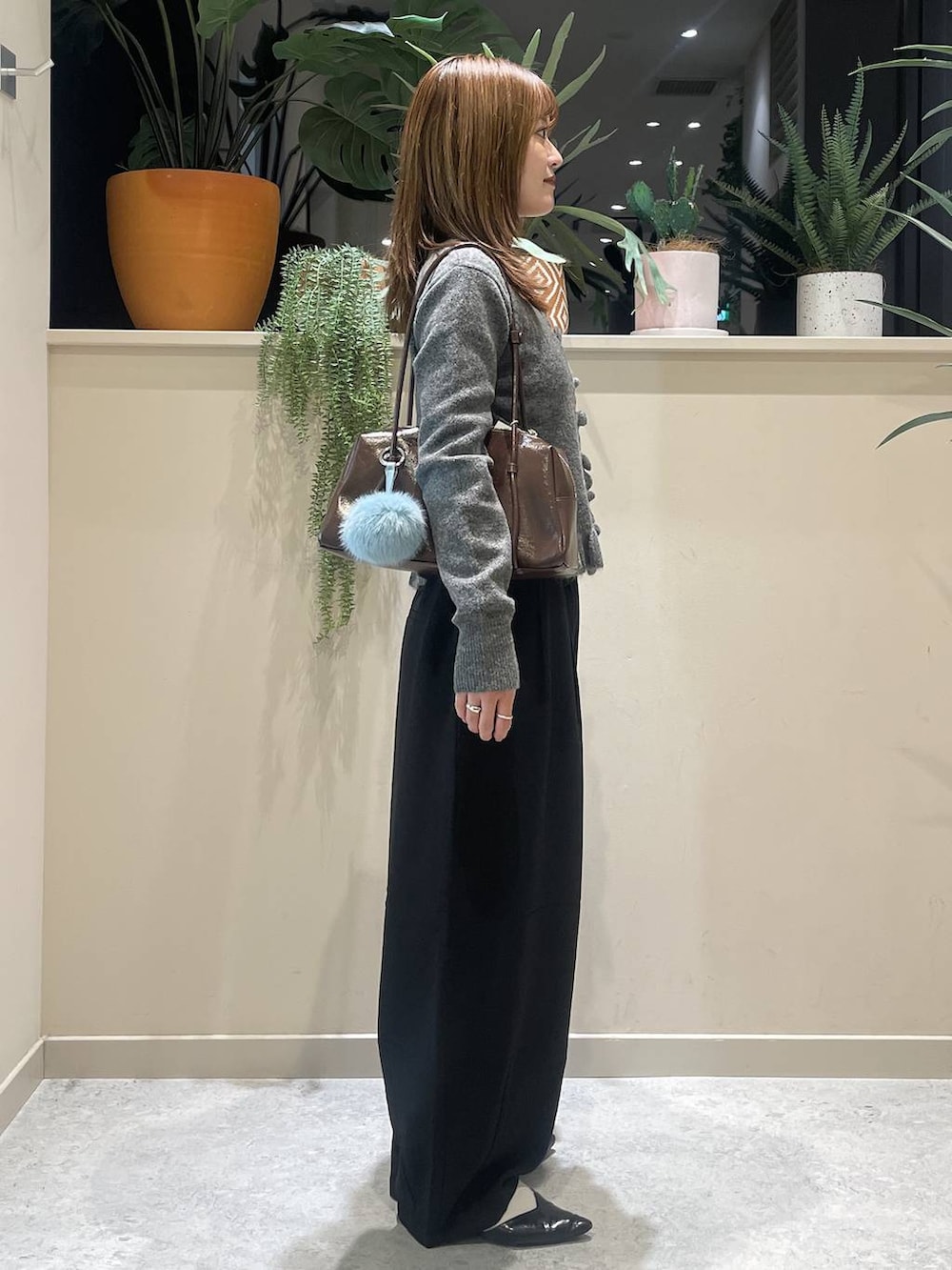 ブラック系のその他パンツ、ブラウン系のボストンバッグ、グレー系のニット/セーターを着用したレディースの秋コーディネートの2枚目の写真
