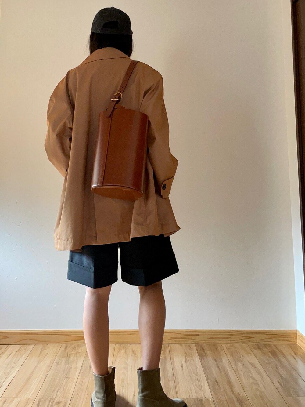 オレンジ系のチェスターコート、ブラック系のカーディガン/ボレロ、グレー系のパンツを着用したレディースの秋コーディネートの3枚目の写真