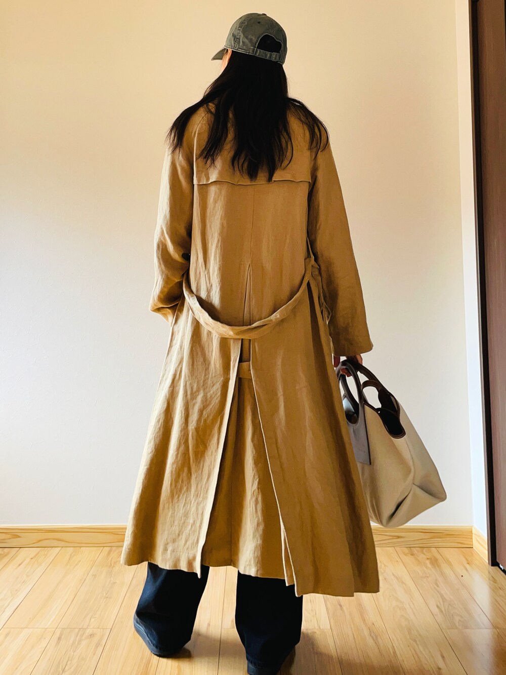 ベージュ系のトレンチコート、ブラック系のデニムパンツ、ブラック系のスニーカーを着用したレディースの春コーディネートの4枚目の写真