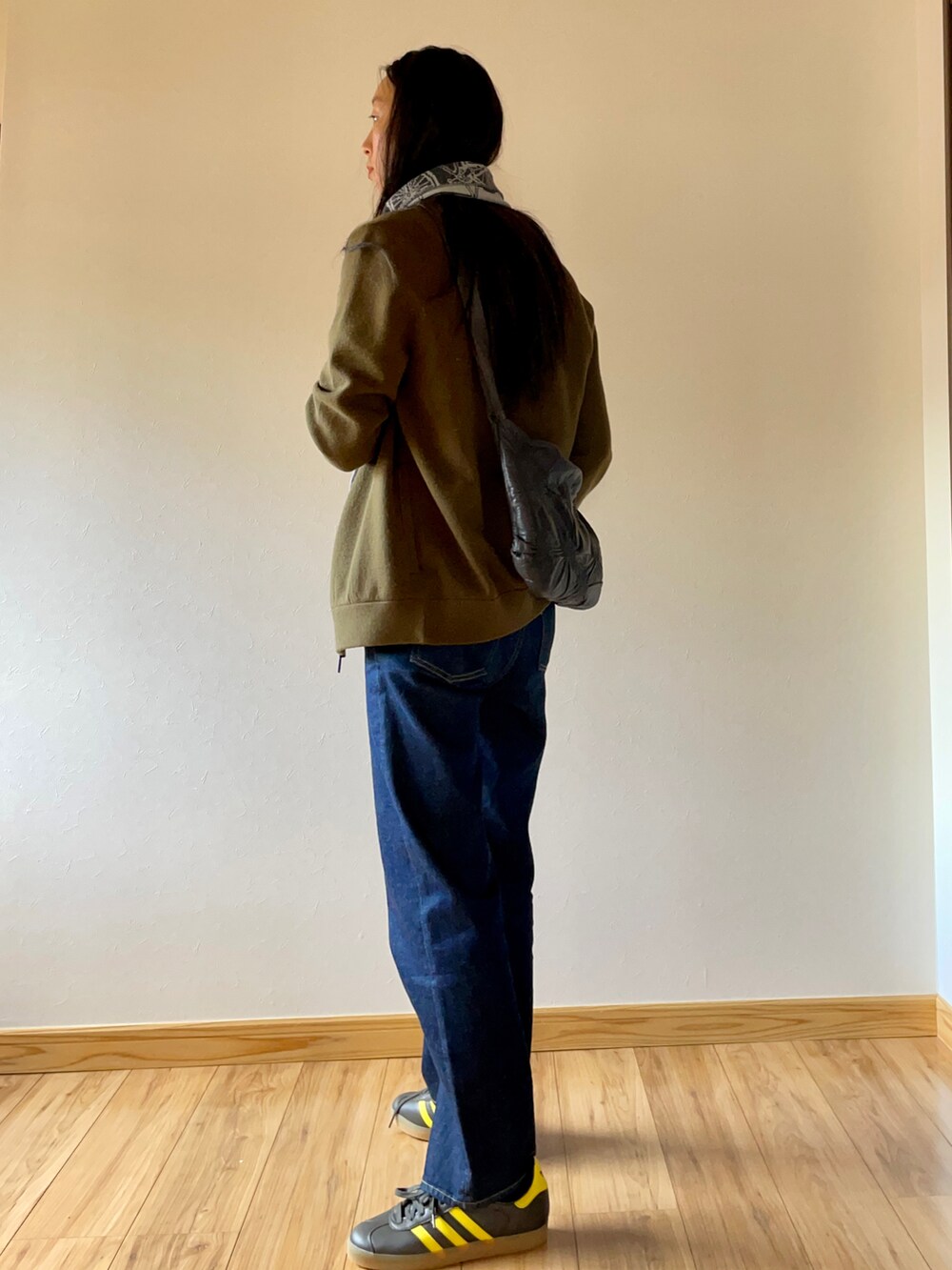 グリーン系のブルゾン、ブルー系のデニムパンツ、グリーン系のスニーカーを着用したレディースの秋コーディネートの2枚目の写真