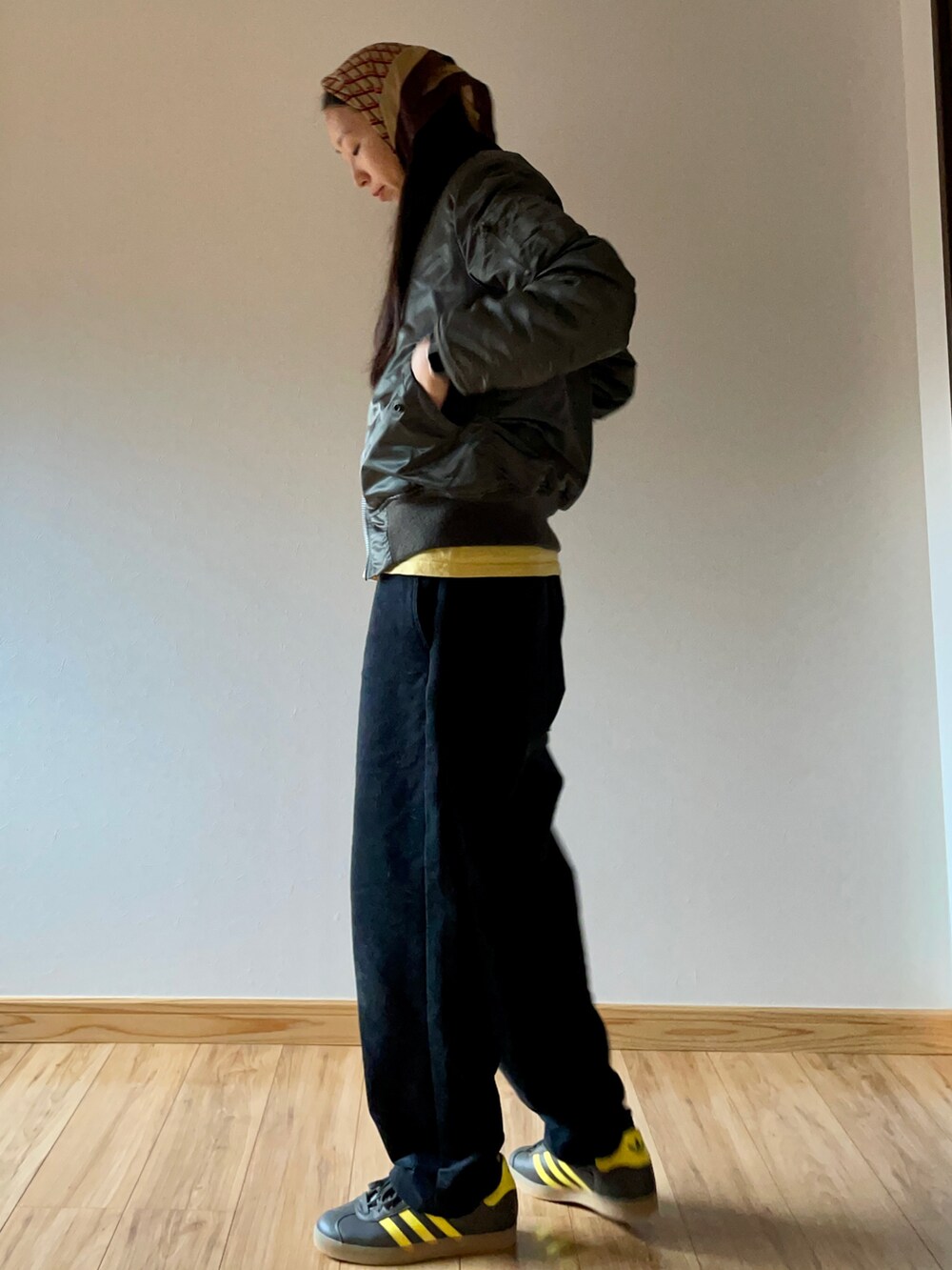 イエロー系のTシャツ/カットソー、ブラック系のスラックス、グリーン系のスニーカーを着用したレディースの秋コーディネートの3枚目の写真