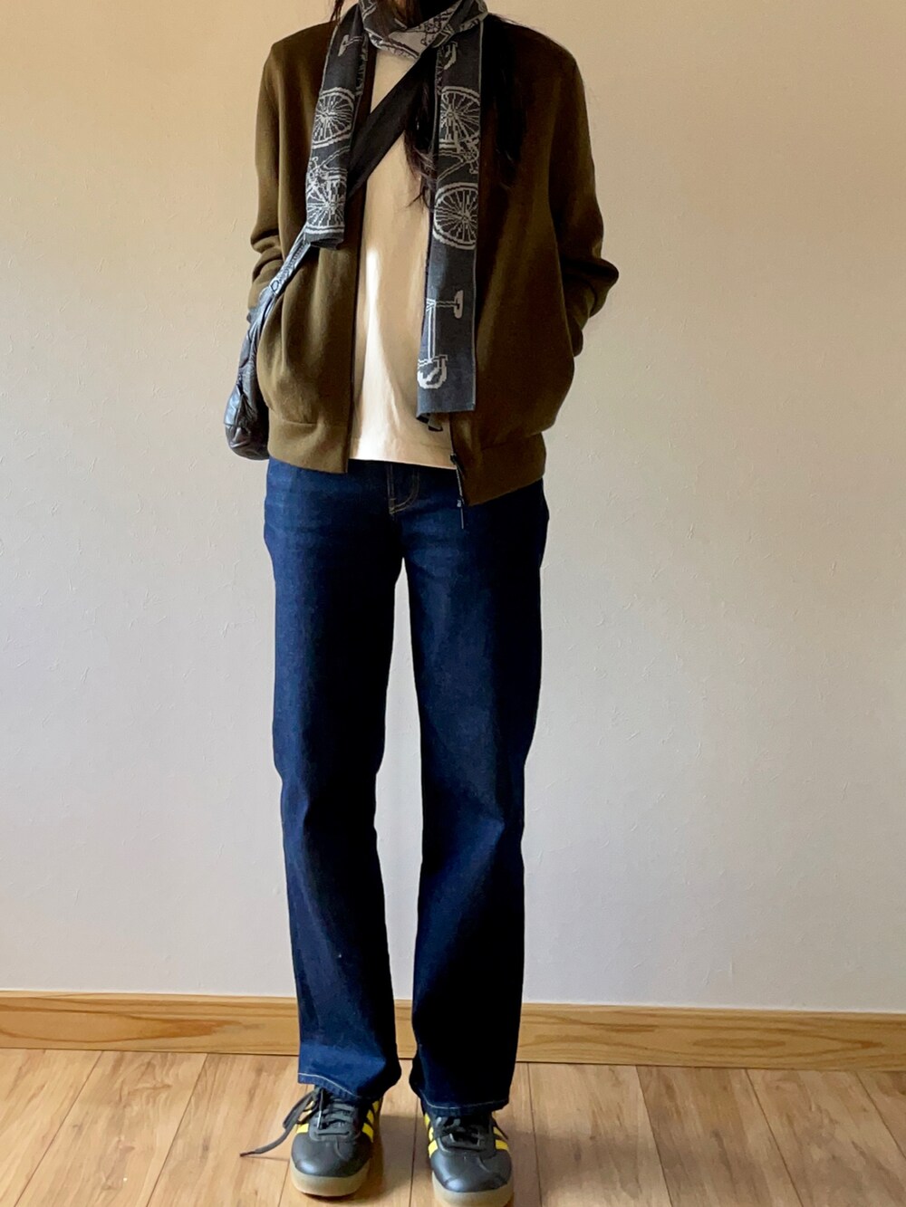 グリーン系のブルゾン、ブルー系のデニムパンツ、グリーン系のスニーカーを着用したレディースの秋コーディネートの3枚目の写真