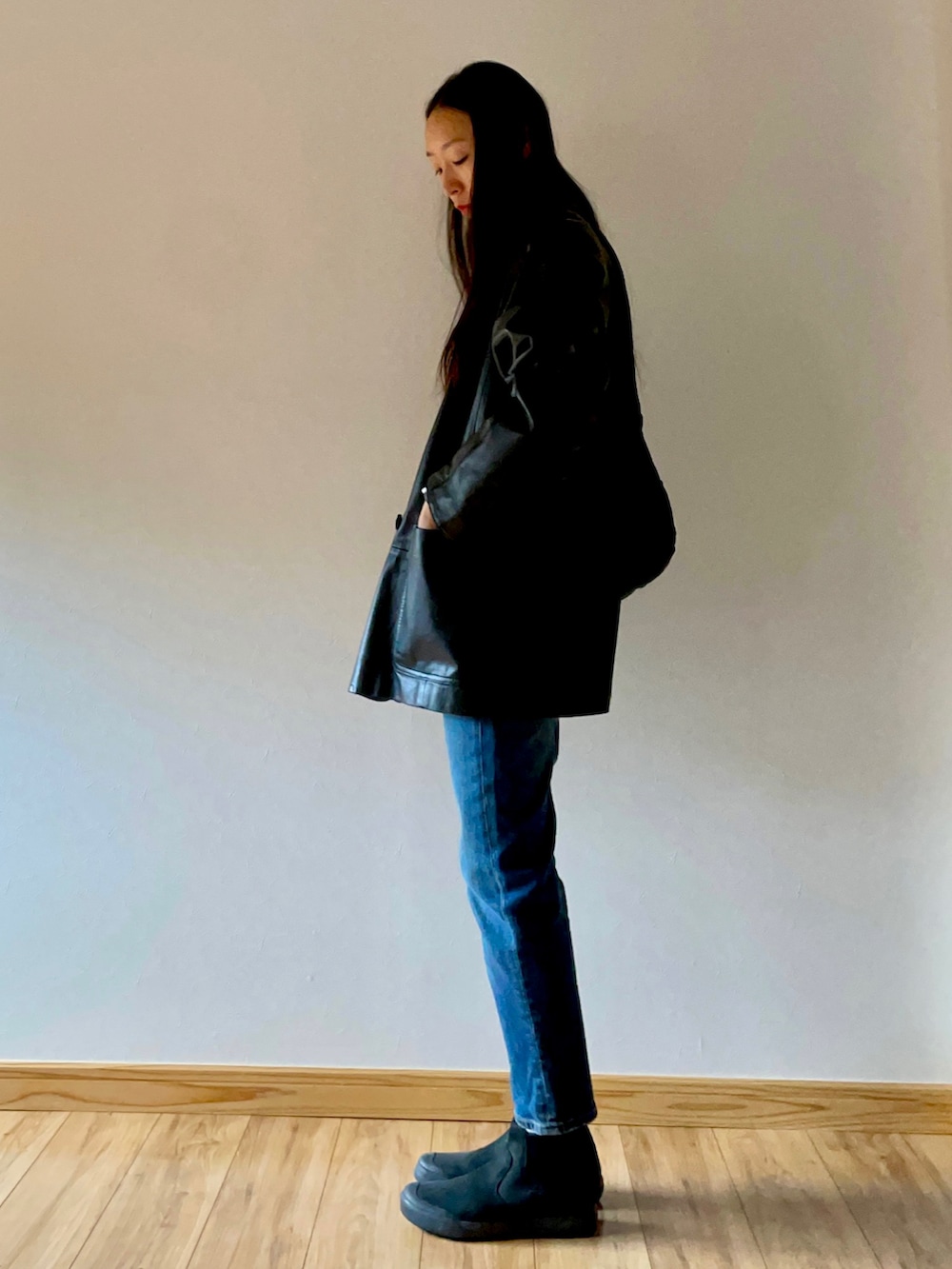 ブラック系のテーラードジャケット、ブルー系のデニムパンツ、ブラック系のブーツを着用したレディースの秋コーディネートの2枚目の写真