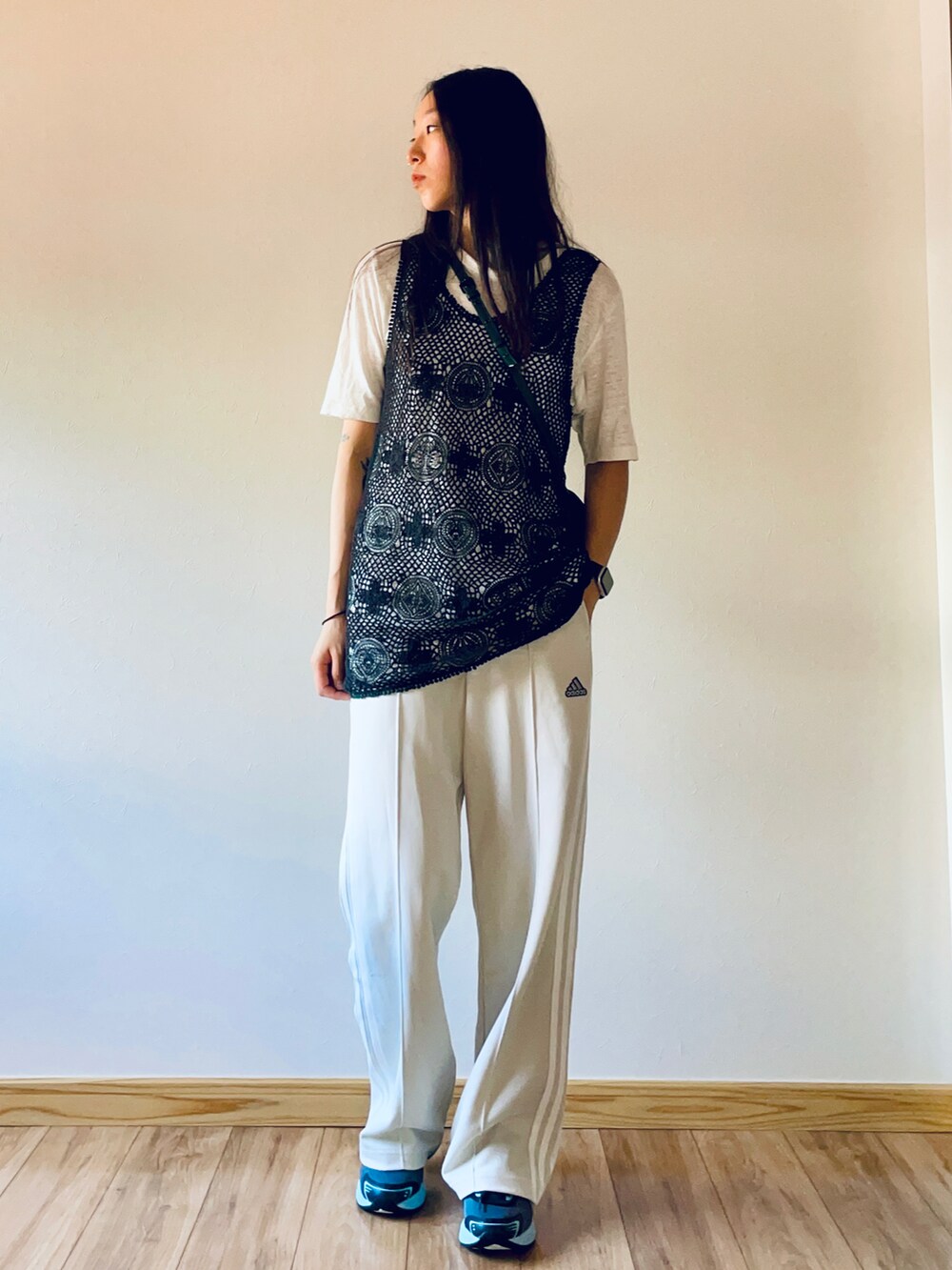 ブラック系のタンクトップ、グリーン系のショルダーバッグ、ホワイト系のパンツを着用したレディースの夏コーディネートの2枚目の写真