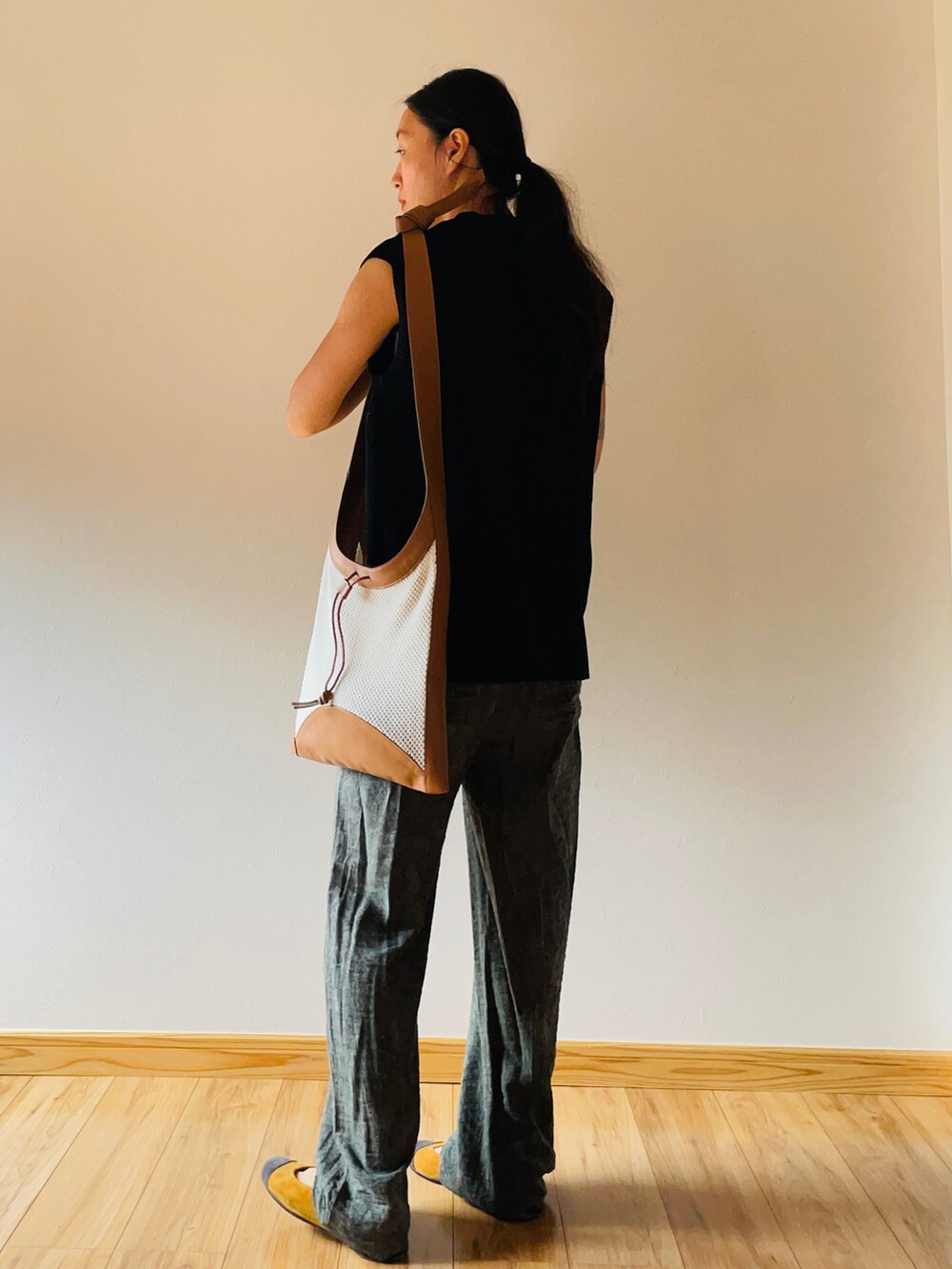 ブラック系のベスト、ベージュ系のショルダーバッグ、グリーン系のパンツを着用したレディースの秋コーディネートの3枚目の写真