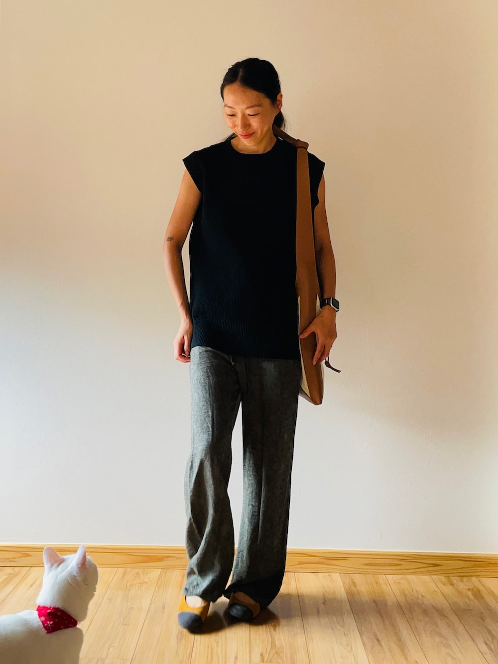 ブラック系のベスト、ベージュ系のショルダーバッグ、グリーン系のパンツを着用したレディースの秋コーディネートの2枚目の写真