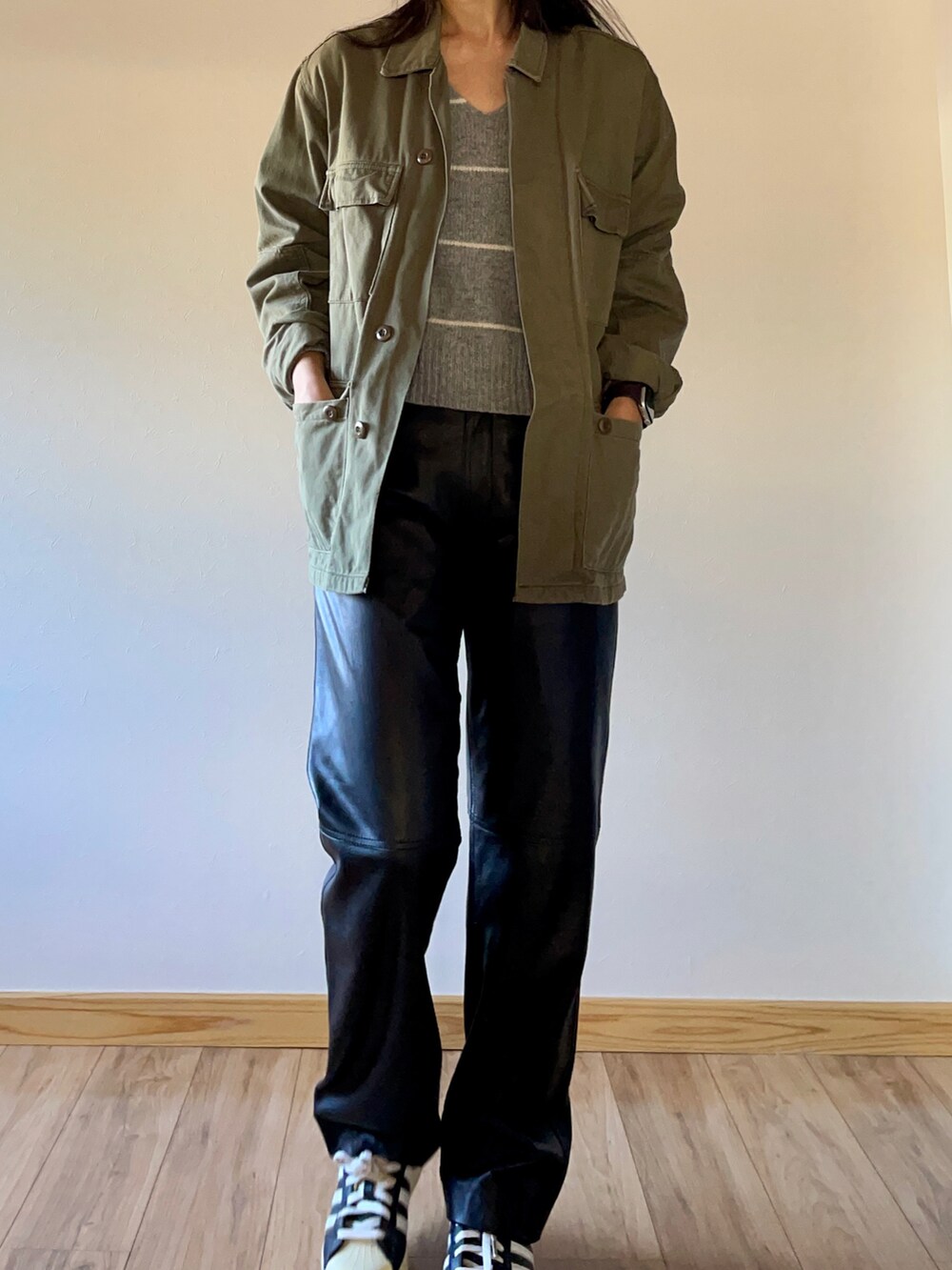 グリーン系のミリタリージャケット、グレー系のニット/セーター、ブラック系のスニーカーを着用したレディースの秋コーディネートの3枚目の写真