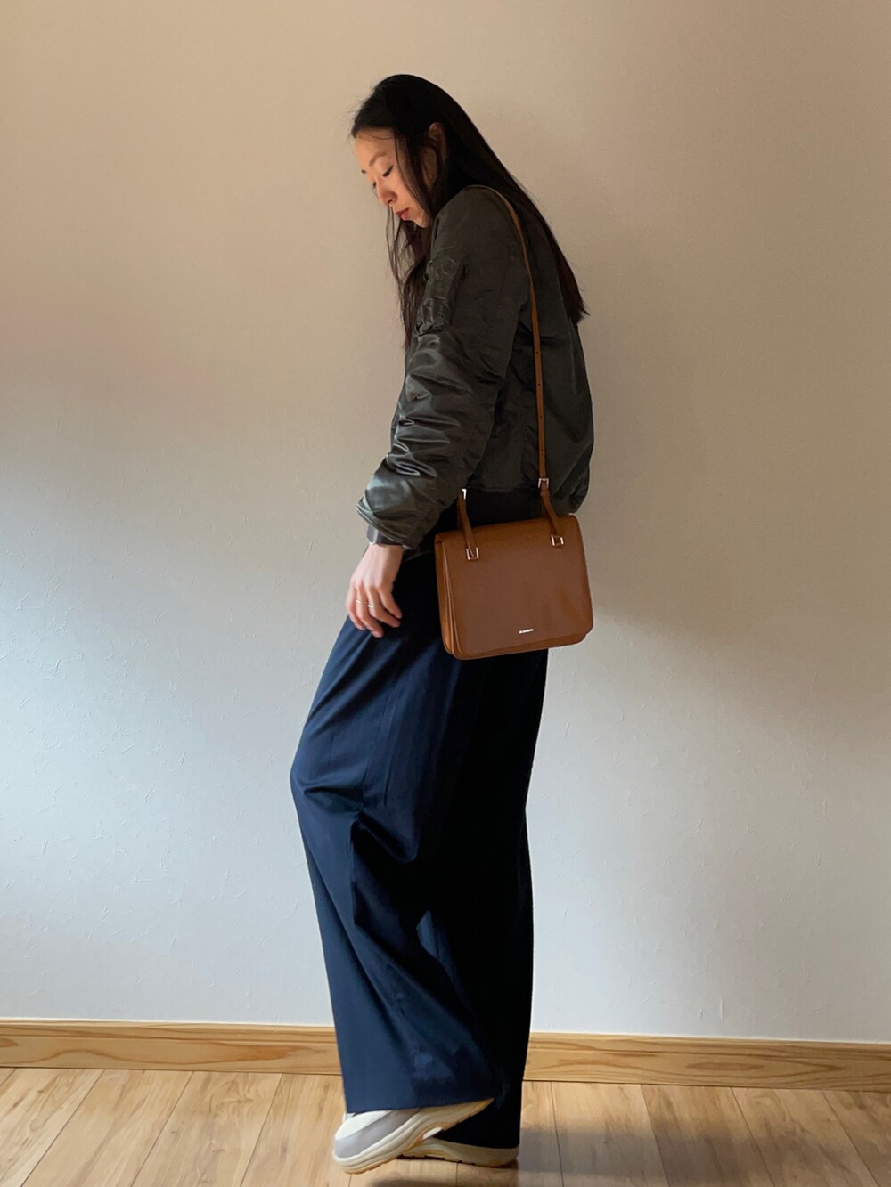 グリーン系のブルゾン、ブラック系のニット/セーター、ブラウン系のショルダーバッグを着用したレディースの秋コーディネートの2枚目の写真