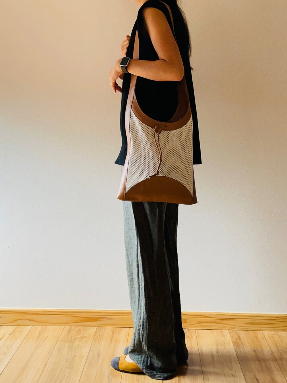 ブラック系のベスト、ベージュ系のショルダーバッグ、グリーン系のパンツを着用したレディースの秋コーディネートの4枚目の写真