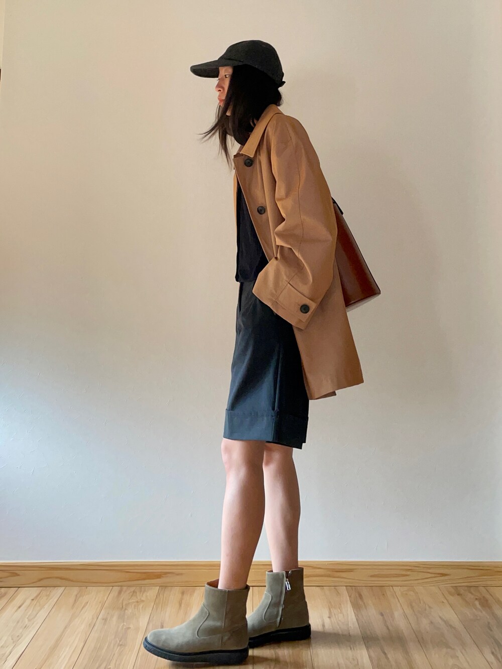 オレンジ系のチェスターコート、ブラック系のカーディガン/ボレロ、グレー系のパンツを着用したレディースの秋コーディネートの2枚目の写真