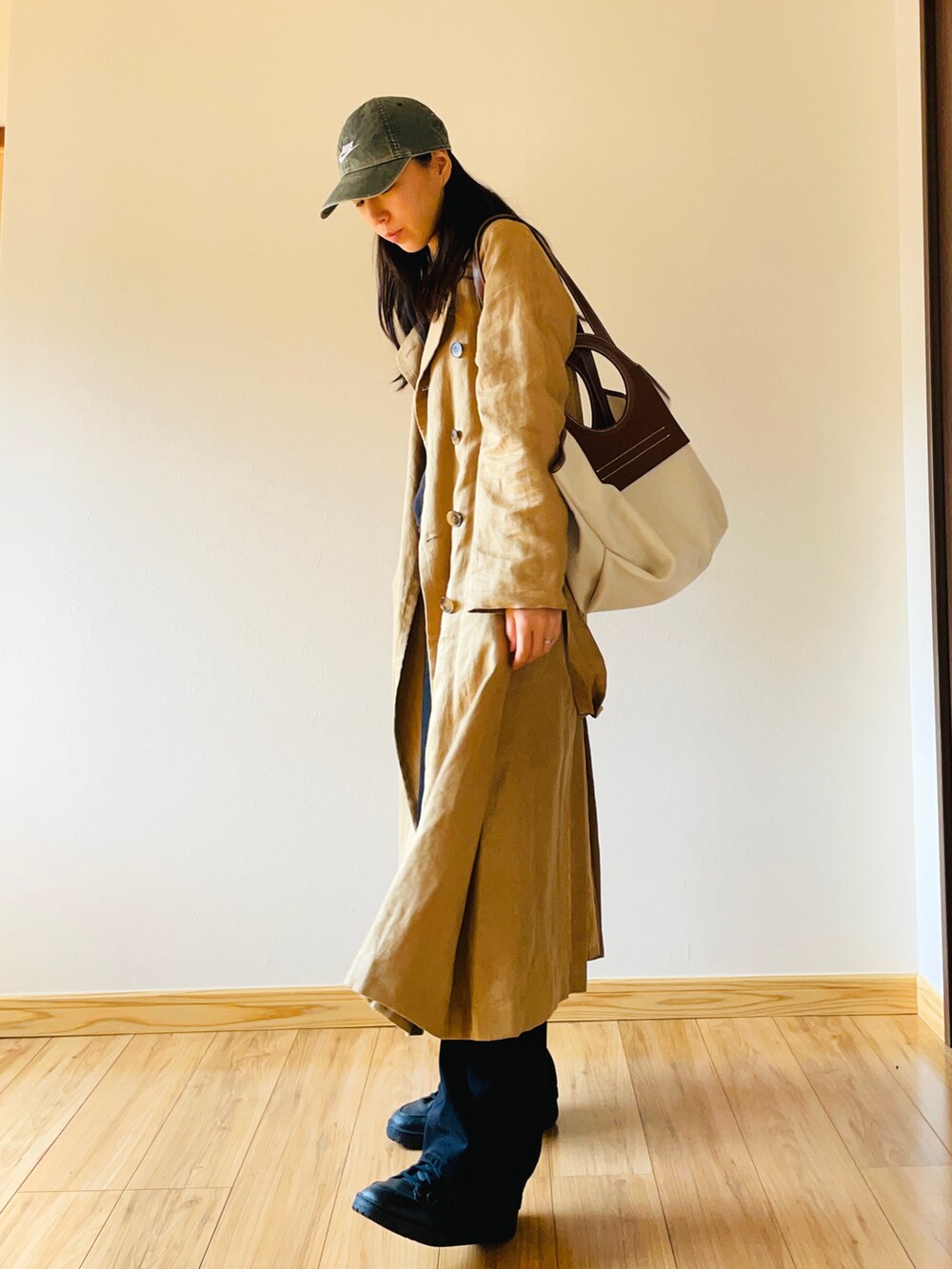 ベージュ系のトレンチコート、ブラック系のデニムパンツ、ブラック系のスニーカーを着用したレディースの春コーディネートの2枚目の写真