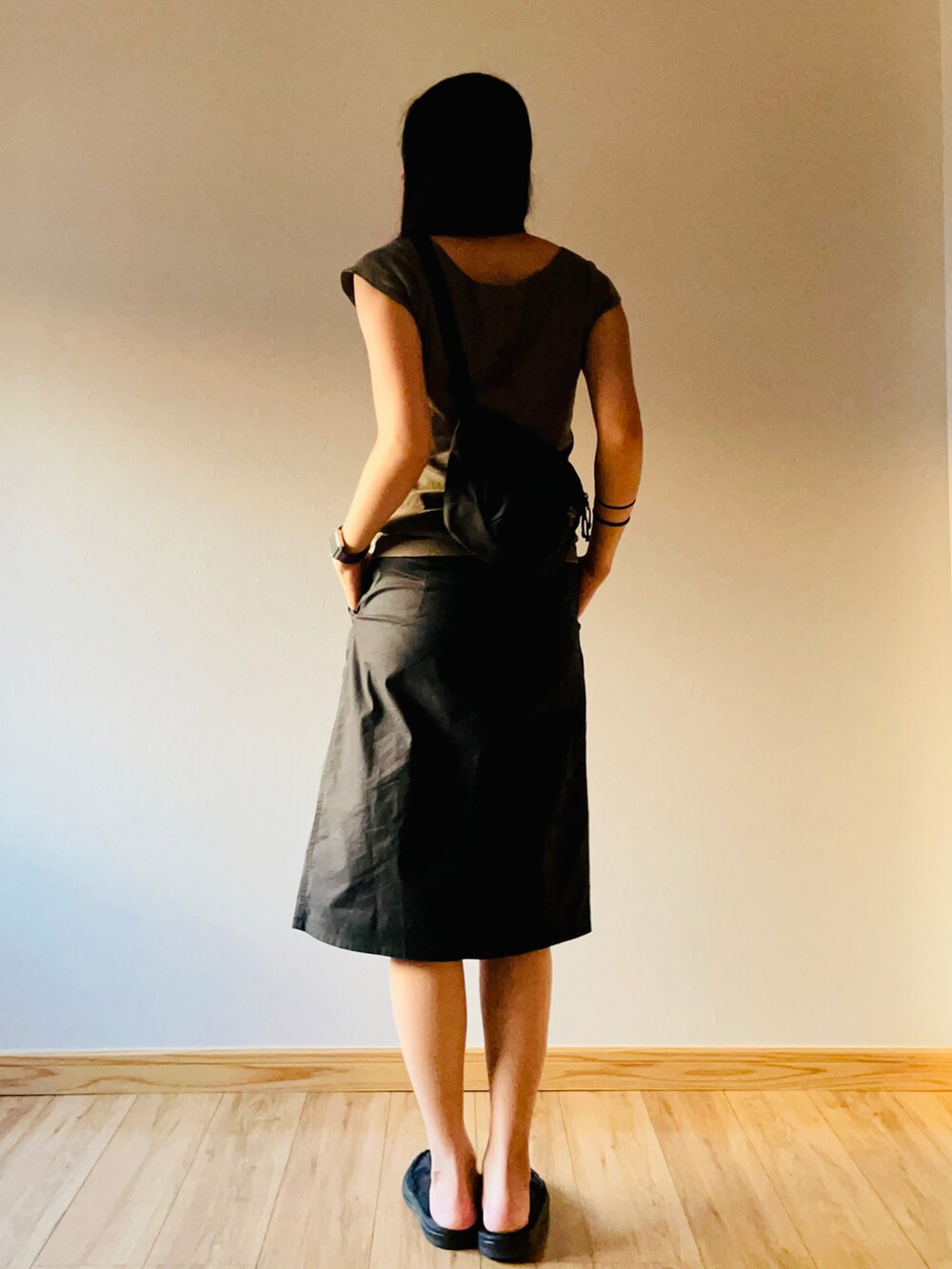 グリーン系のTシャツ/カットソー、ブラック系のスカート、ブラック系のサンダルを着用したレディースの夏コーディネートの2枚目の写真