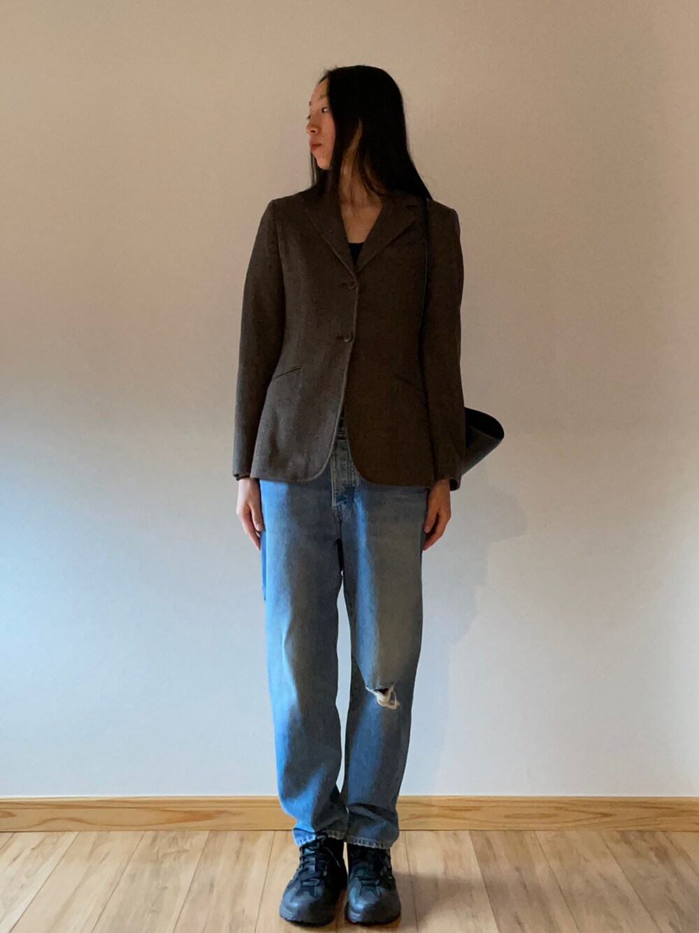 ブラウン系のテーラードジャケット、ブラック系のショルダーバッグ、ブルー系のデニムパンツを着用したレディースの秋コーディネートの2枚目の写真