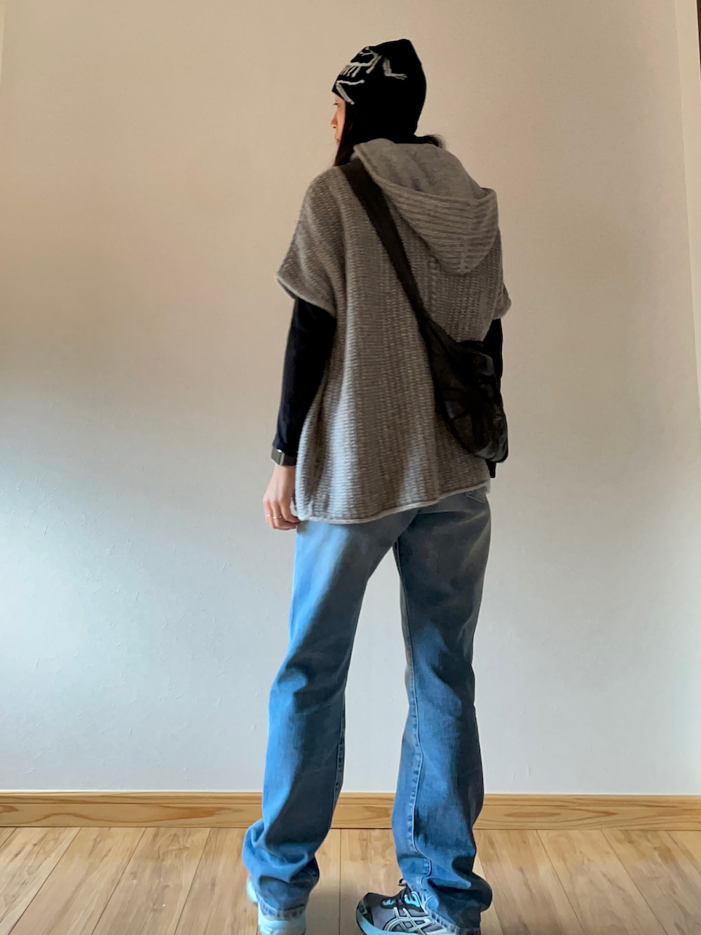 ブルー系のデニムパンツ、グレー系のスニーカー、ブラック系のショルダーバッグを着用したレディースの秋コーディネートの2枚目の写真