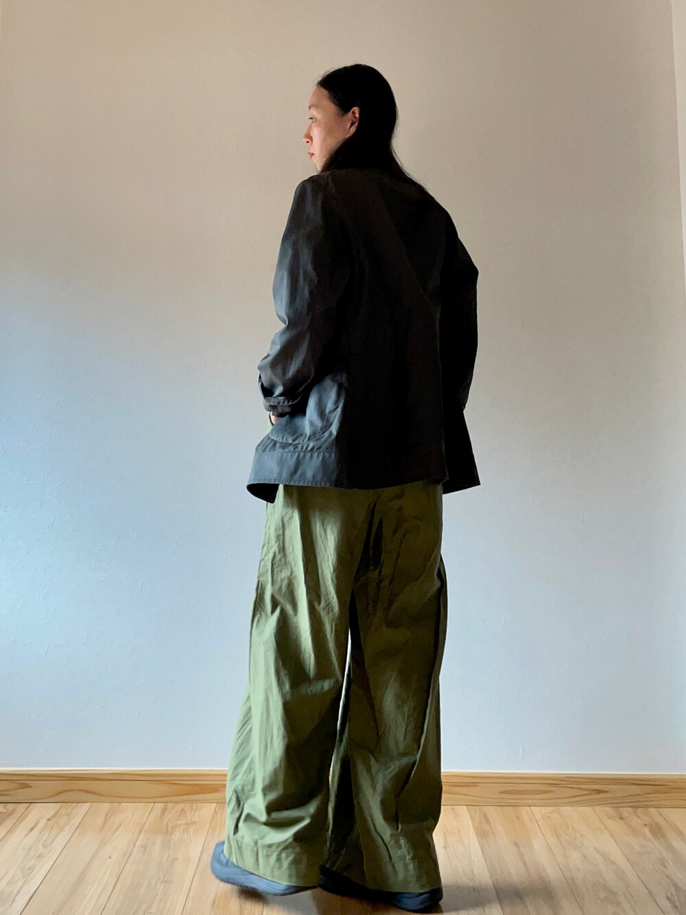 グリーン系のミリタリージャケット、ブラウン系のニット/セーター、グリーン系のスラックスを着用したレディースの秋コーディネートの2枚目の写真