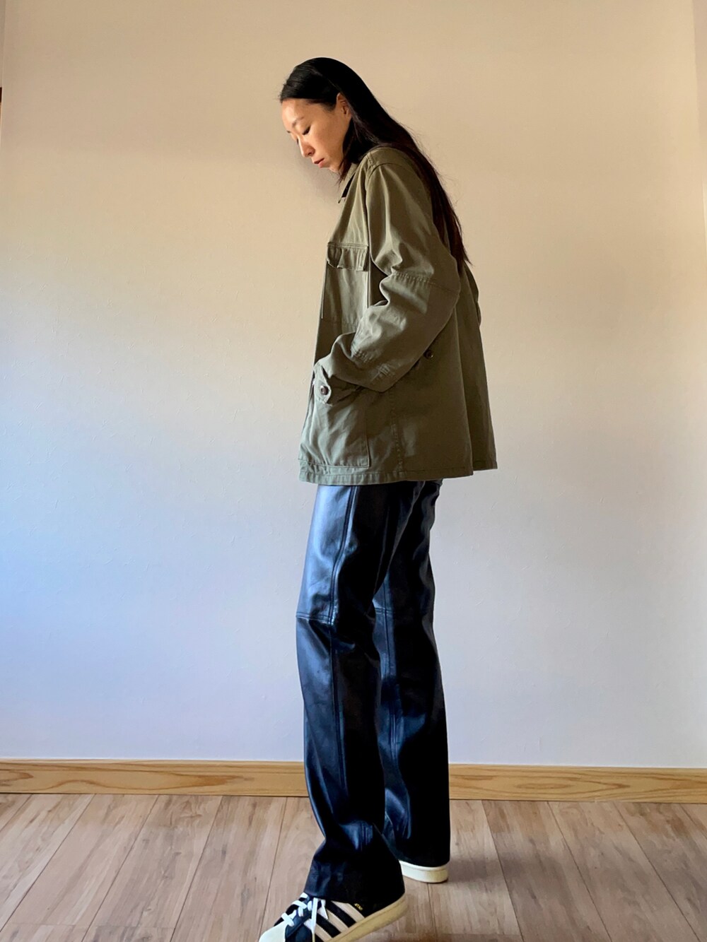 グリーン系のミリタリージャケット、グレー系のニット/セーター、ブラック系のスニーカーを着用したレディースの秋コーディネートの2枚目の写真