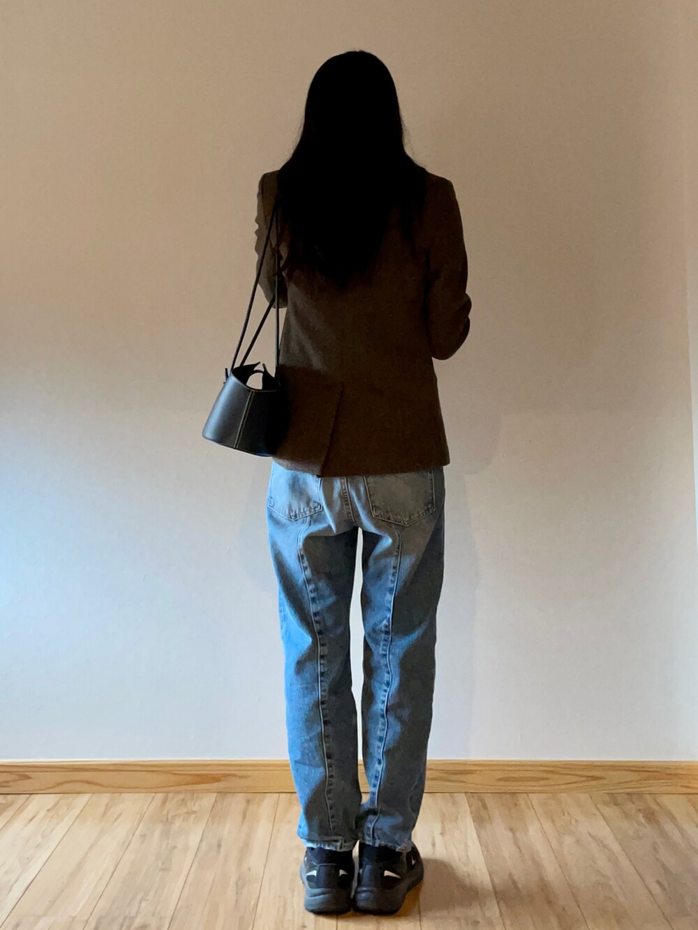 ブラウン系のテーラードジャケット、ブラック系のショルダーバッグ、ブルー系のデニムパンツを着用したレディースの秋コーディネートの3枚目の写真