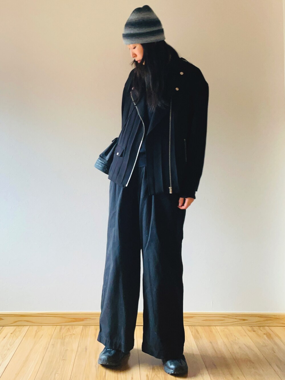 ブラック系のライダースジャケット、ブラック系のチノパンツ、ブラック系のスニーカーを着用したレディースの春コーディネートの3枚目の写真