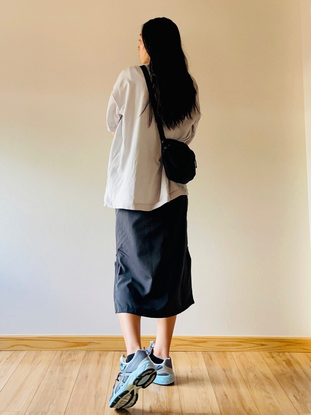 グレー系のポロシャツ、ブラック系のボディバッグ/ウエストポーチ、ブラック系のスカートを着用したレディースの夏コーディネートの2枚目の写真