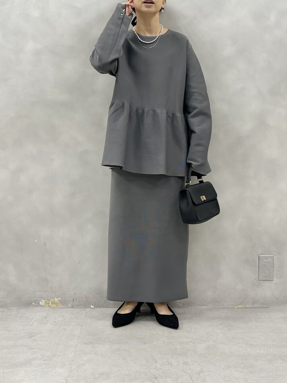 グレー系のニット/セーター、グレー系のスカート、ブラック系のショルダーバッグを着用したレディースの春コーディネートの5枚目の写真