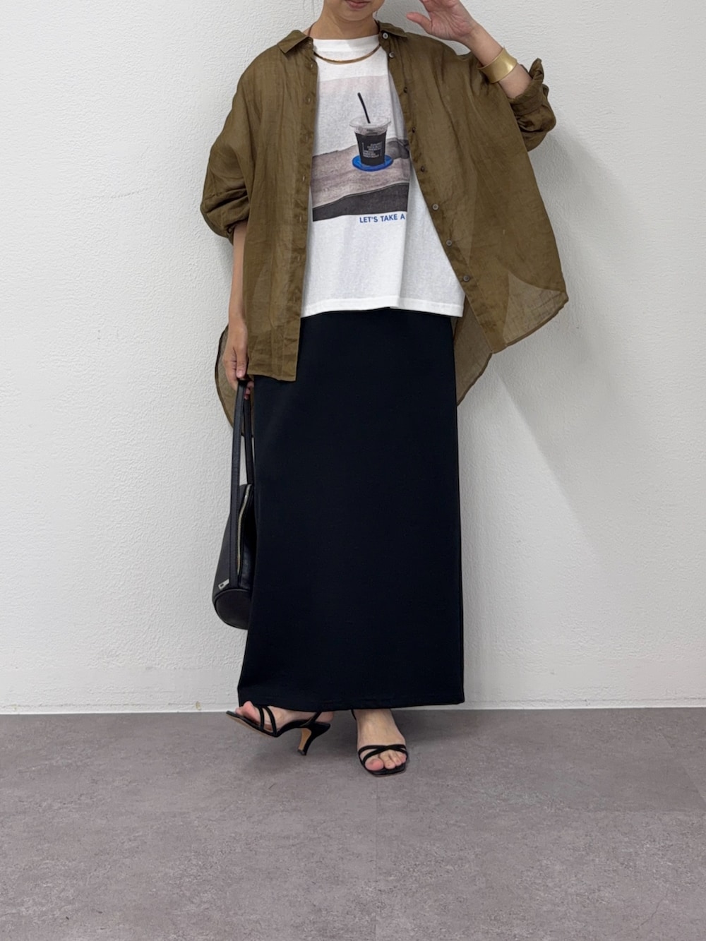 ブラック系のスカート、ブラウン系のシャツ/ブラウス、ホワイト系のTシャツ/カットソーを着用したレディースの夏コーディネートの2枚目の写真