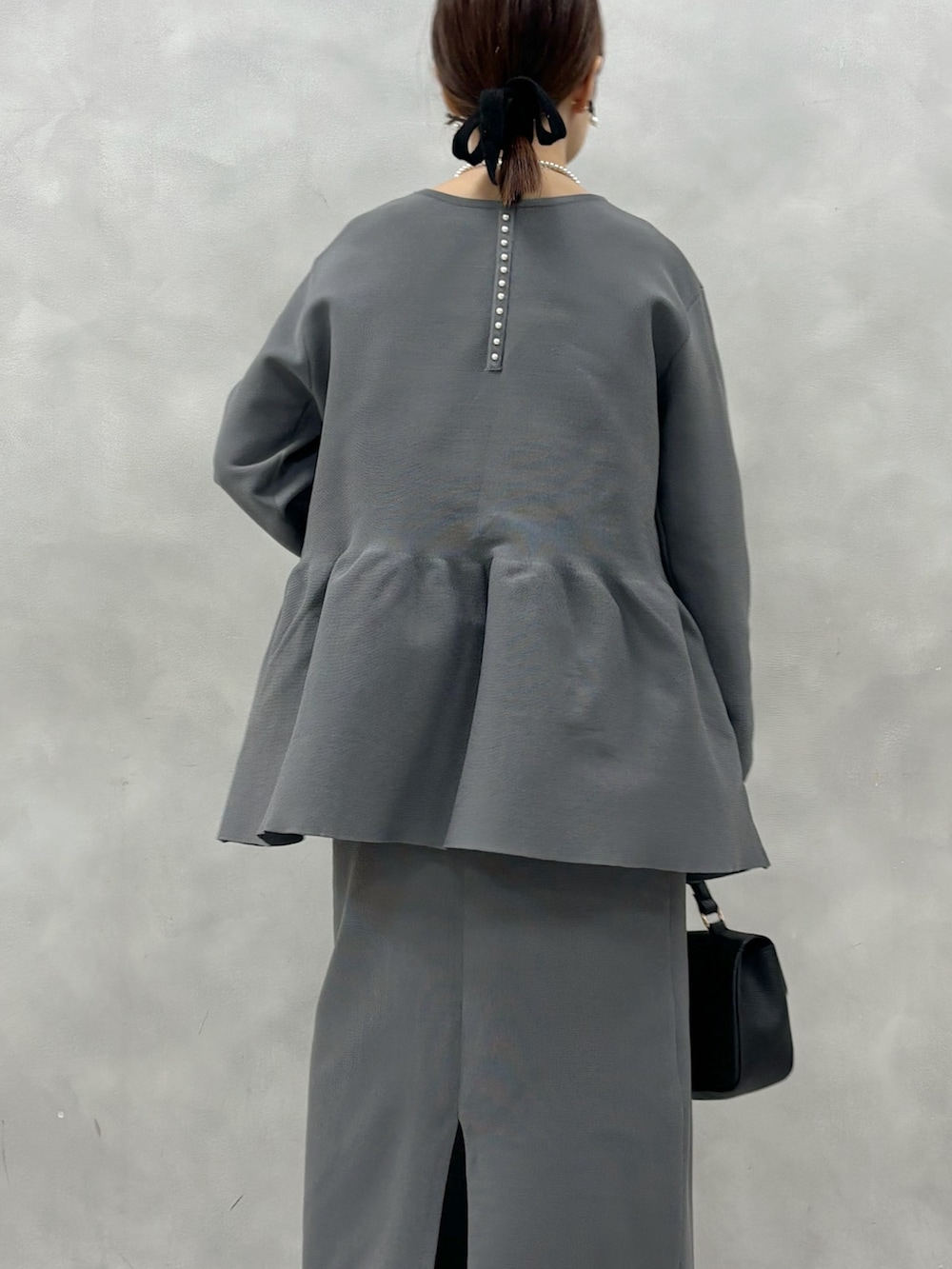 グレー系のニット/セーター、グレー系のスカート、ブラック系のショルダーバッグを着用したレディースの春コーディネートの4枚目の写真