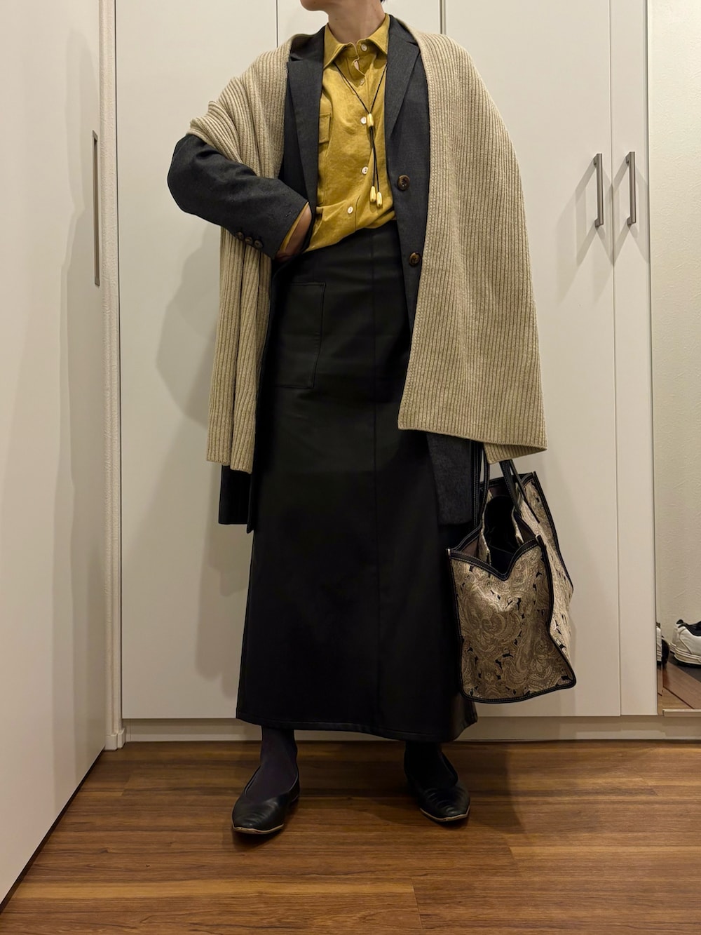 ブラック系のトートバッグ、イエロー系のシャツ/ブラウス、ブラック系のスカートを着用したレディースの秋コーディネートの2枚目の写真
