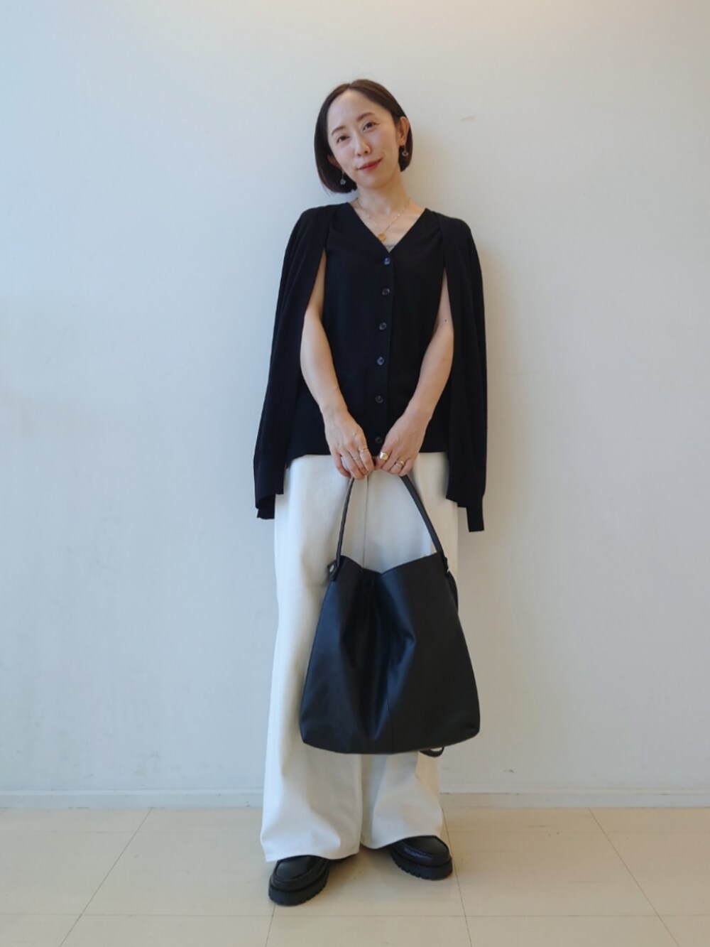 ブラック系のカーディガン/ボレロ、ホワイト系のデニムパンツ、ブラック系のトートバッグを着用したレディースの秋コーディネートの2枚目の写真