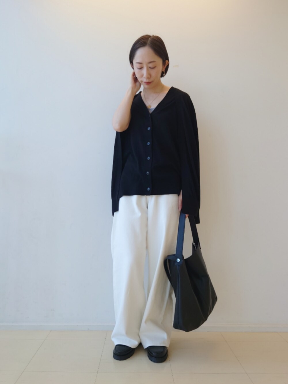ブラック系のカーディガン/ボレロ、ホワイト系のデニムパンツ、ブラック系のトートバッグを着用したレディースの秋コーディネートの3枚目の写真