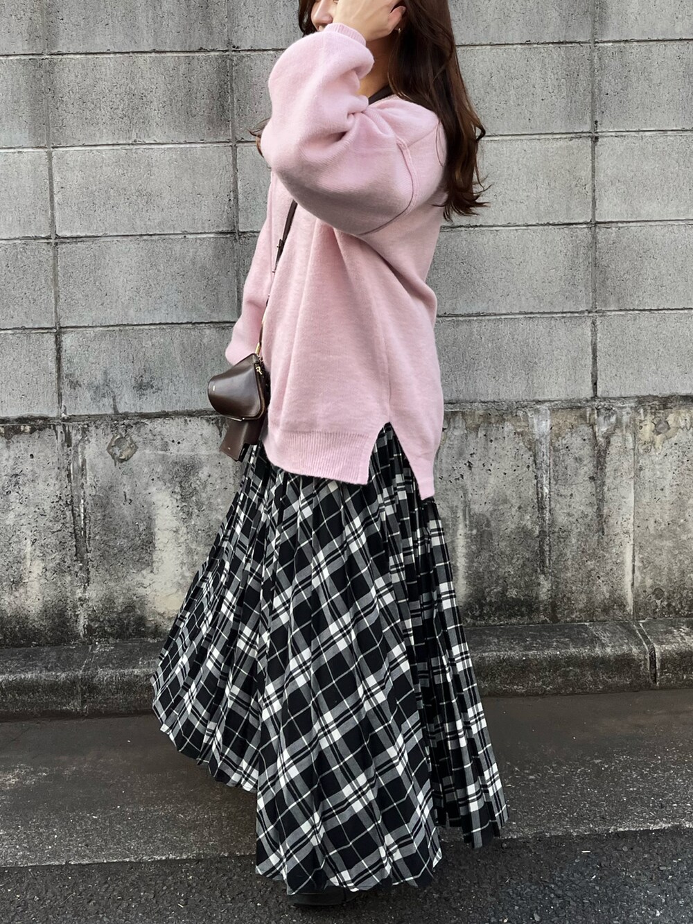 ピンク系のニット/セーター、ブラック系のスカート、ブラック系のブーツを着用したレディースの冬コーディネートの2枚目の写真