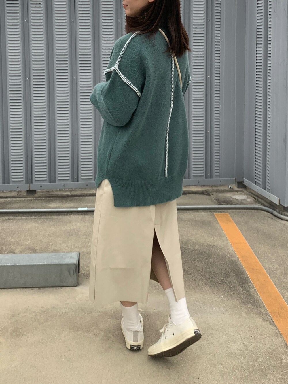 ブルー系のニット/セーター、ホワイト系のスカート、ホワイト系のスニーカーを着用したレディースの春コーディネートの2枚目の写真