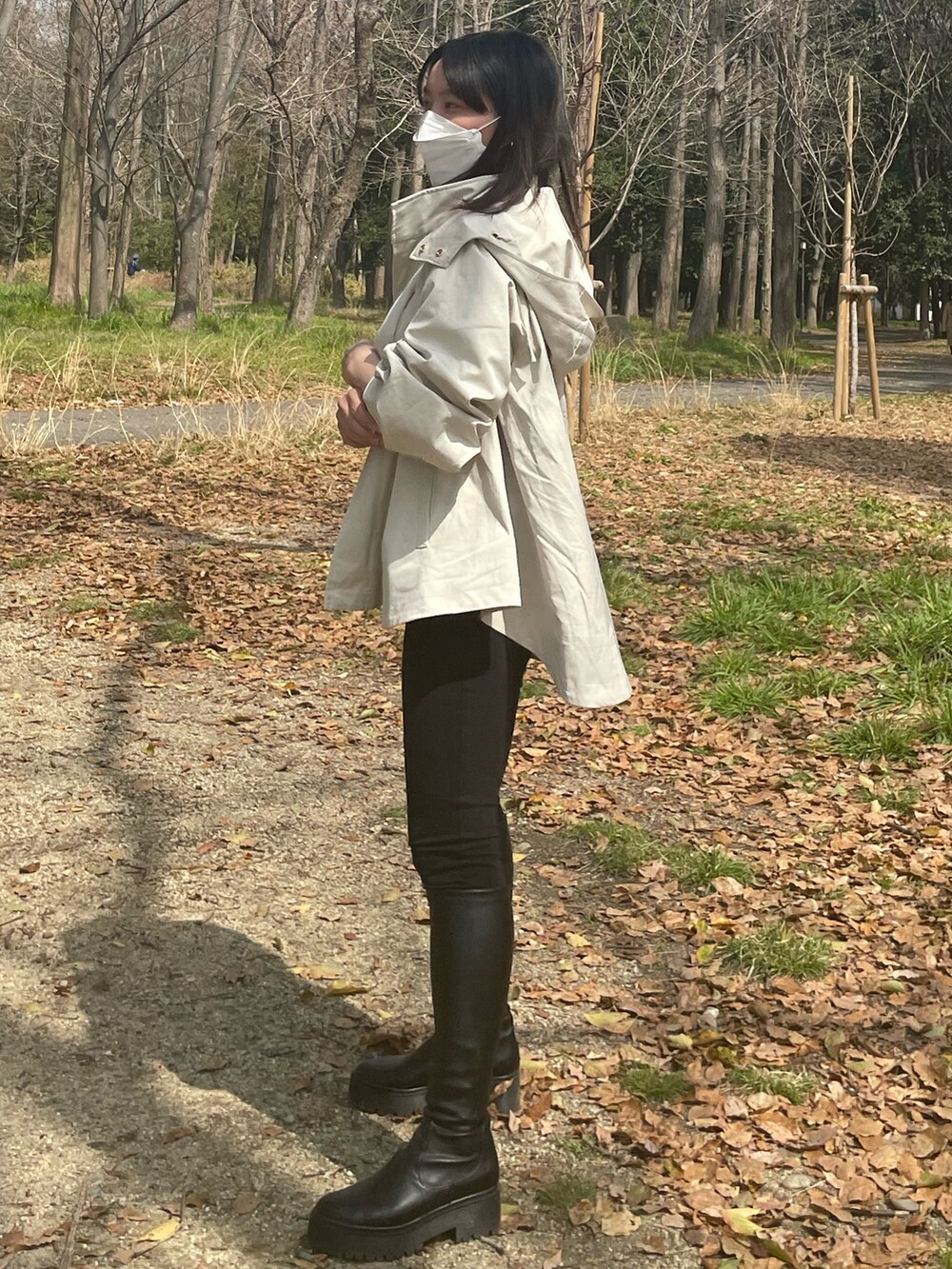 ベージュ系のマウンテンパーカー、ブルー系のニット/セーター、ブラック系のブーツを着用したレディースの春コーディネートの2枚目の写真