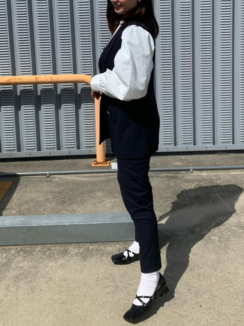 ホワイト系のシャツ/ブラウス、ブルー系のベスト、ブルー系のスラックスを着用したレディースの春コーディネートの2枚目の写真