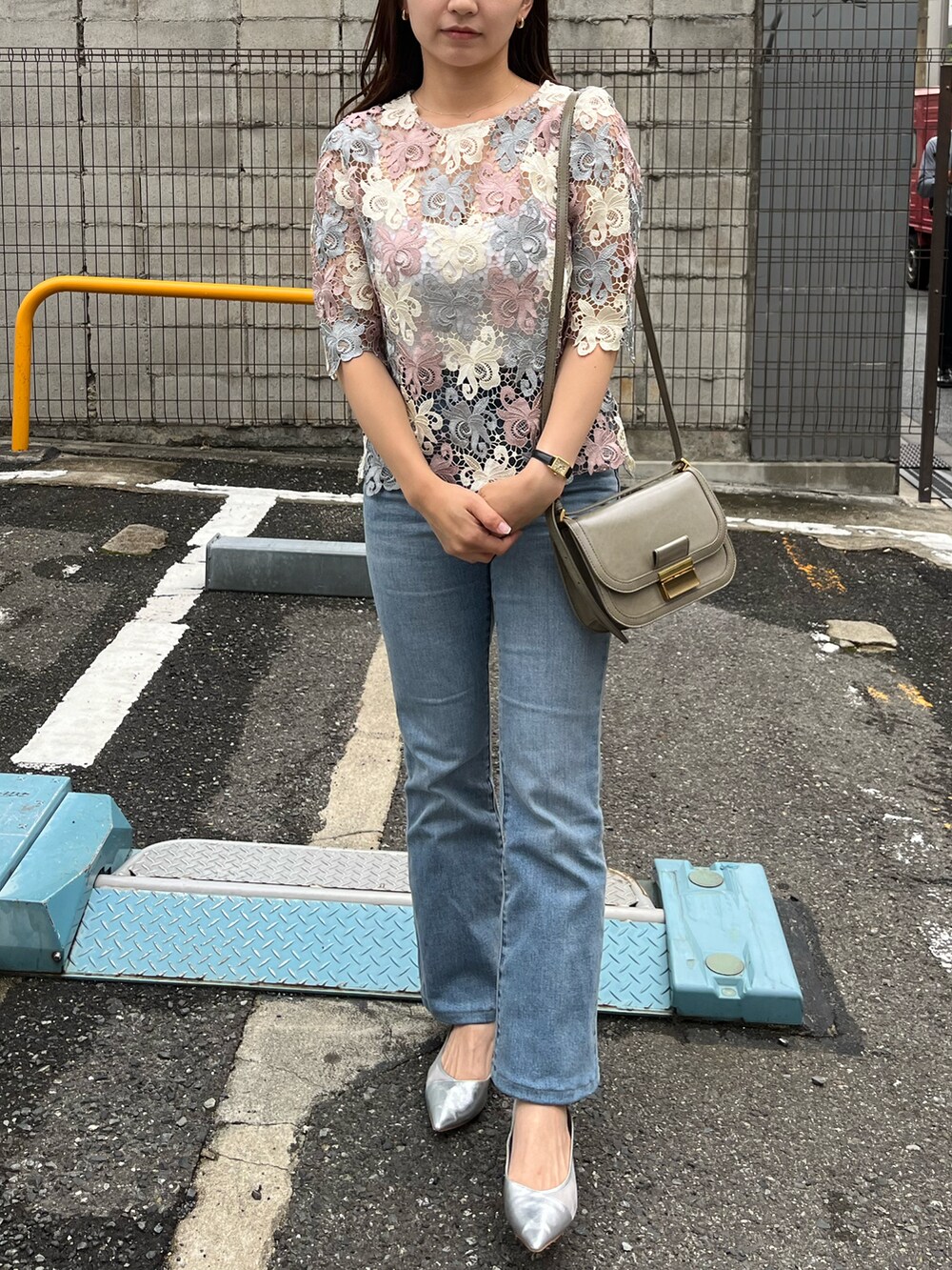 ピンク系のトップス、ベージュ系のショルダーバッグ、シルバー系のパンプスを着用したレディースの夏コーディネートの2枚目の写真