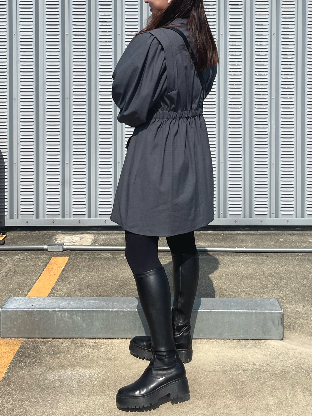 グレー系のワンピース、ブラック系のショルダーバッグ、ブラック系のブーツを着用したレディースの春コーディネートの2枚目の写真