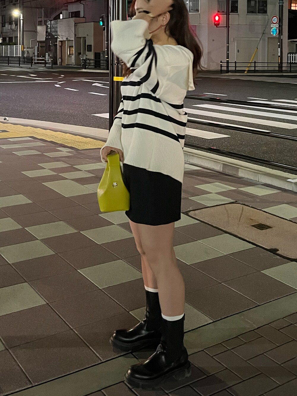 イエロー系のハンドバッグ、ホワイト系のニット/セーター、ブラック系のパンツを着用したレディースの秋コーディネートの2枚目の写真