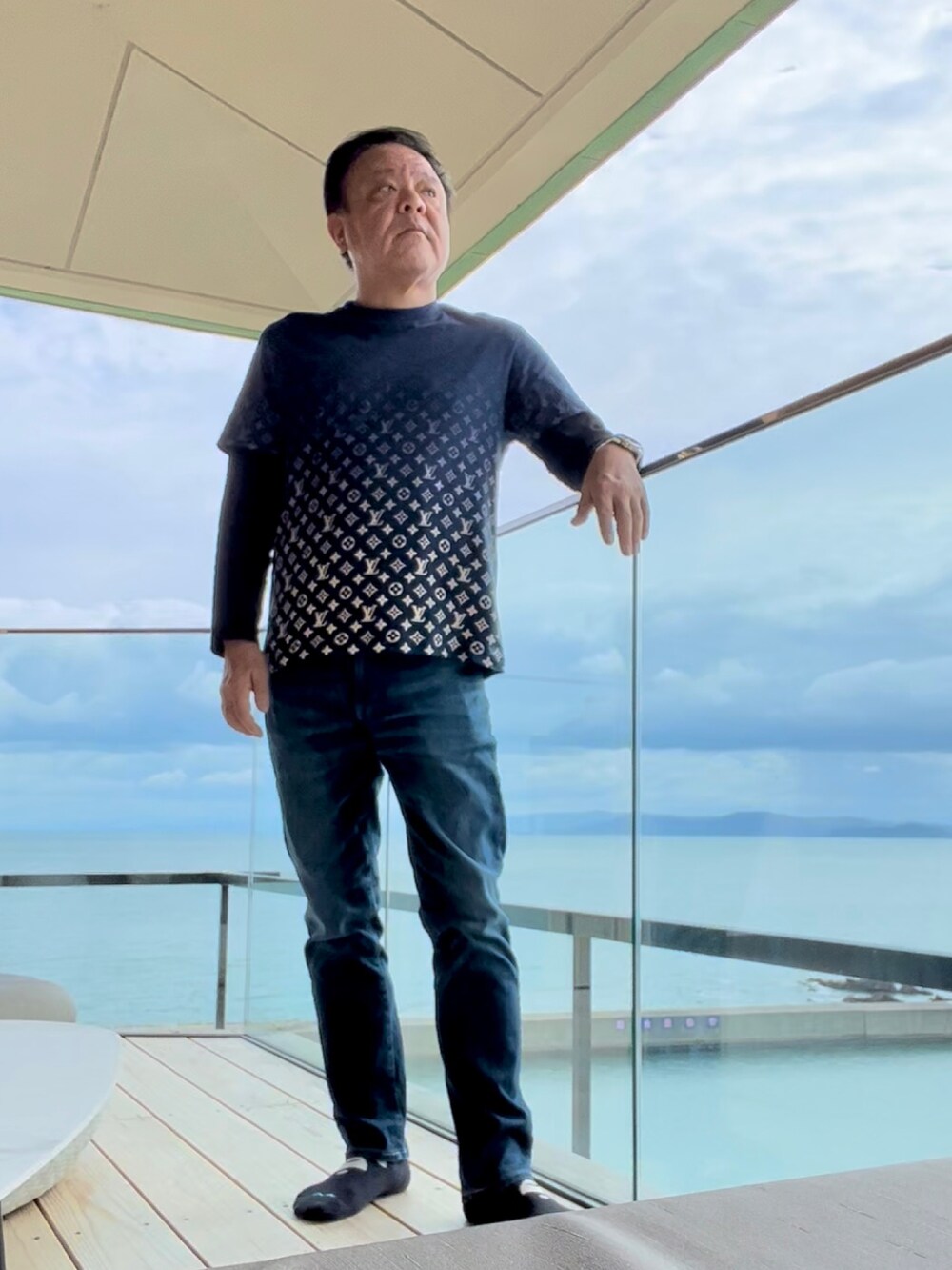 ブルー系のTシャツ/カットソー、ブラック系のスニーカー、ブルー系のデニムパンツを着用したメンズの秋コーディネートの2枚目の写真