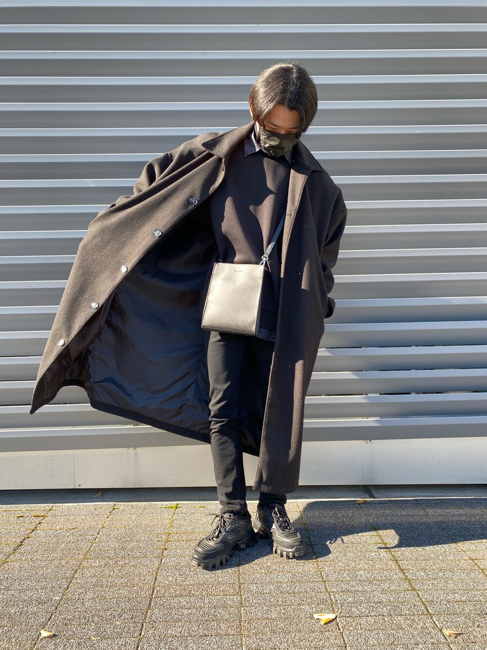 ブラック系のパンツ、ブラック系のステンカラーコート、ブラック系のショルダーバッグを着用したメンズの冬コーディネートの5枚目の写真