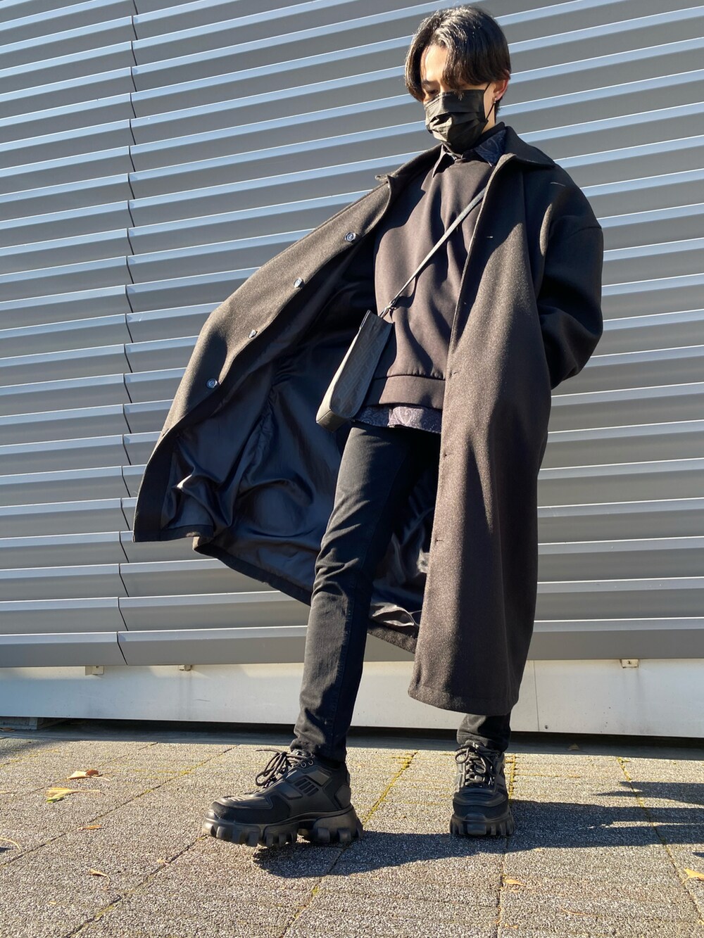 ブラック系のパンツ、ブラック系のステンカラーコート、ブラック系のショルダーバッグを着用したメンズの冬コーディネートの3枚目の写真