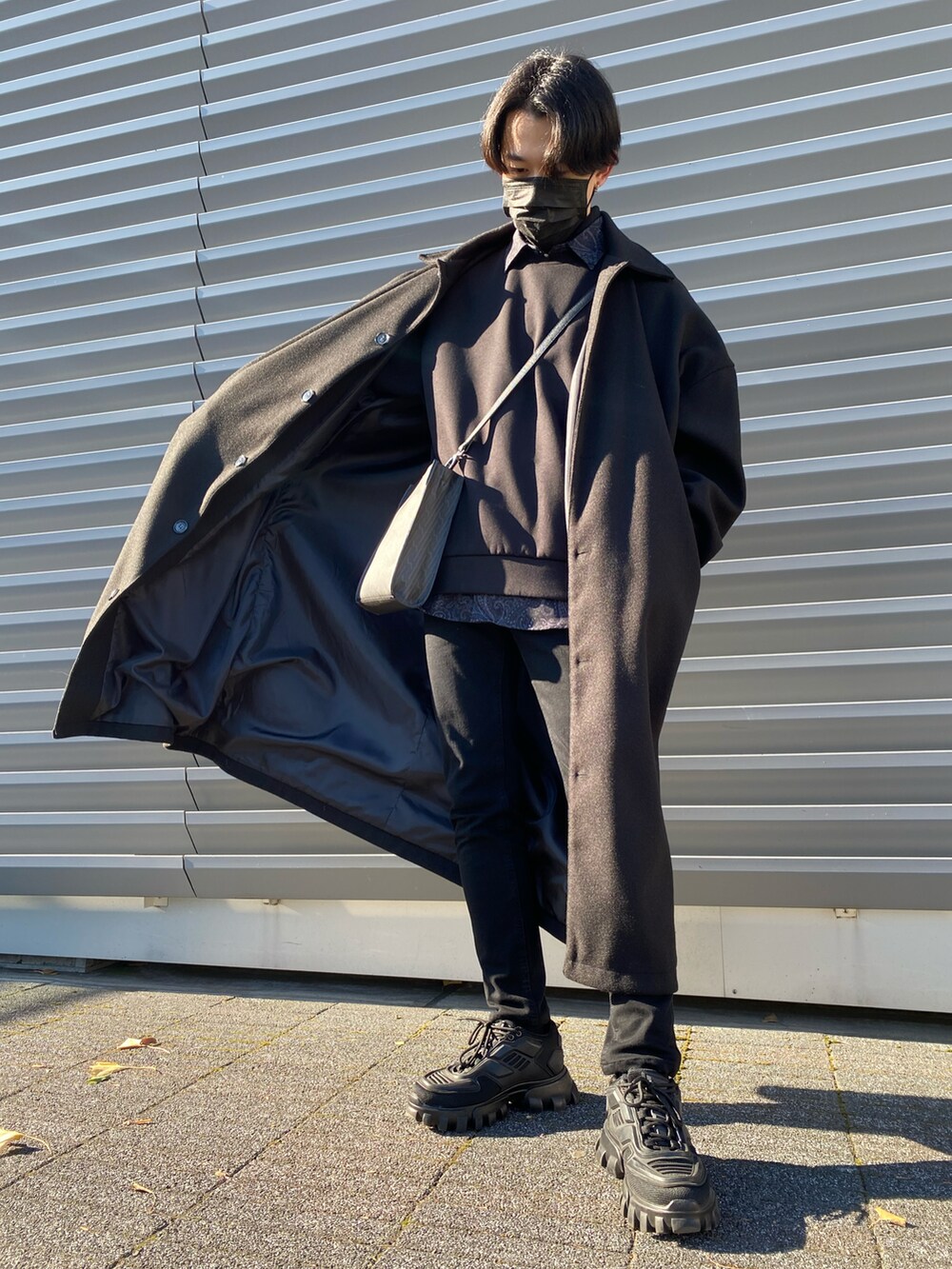 ブラック系のパンツ、ブラック系のステンカラーコート、ブラック系のショルダーバッグを着用したメンズの冬コーディネートの4枚目の写真